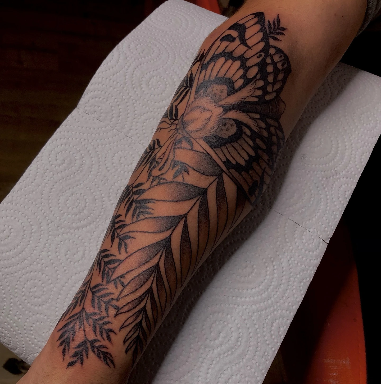 Fairy moth with botanical leaves cascading down forearm