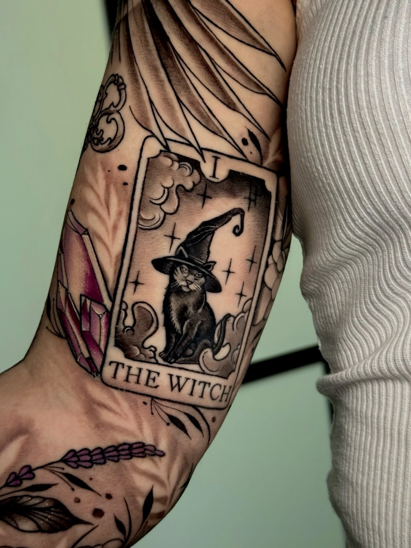 'The Witch' tarot card with black cat in witch hat, crystals at side