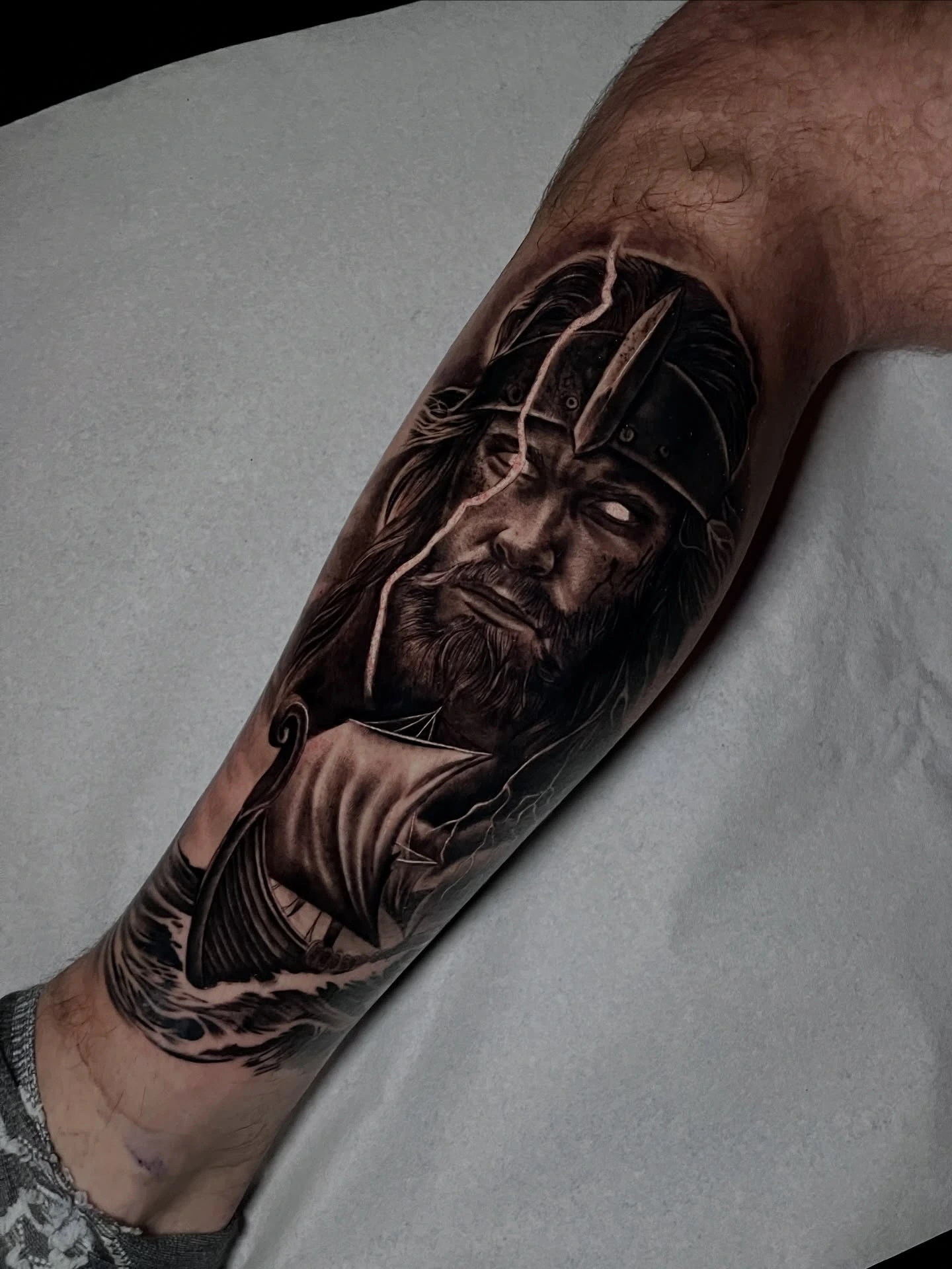 Viking warrior portrait with helmet and longship below