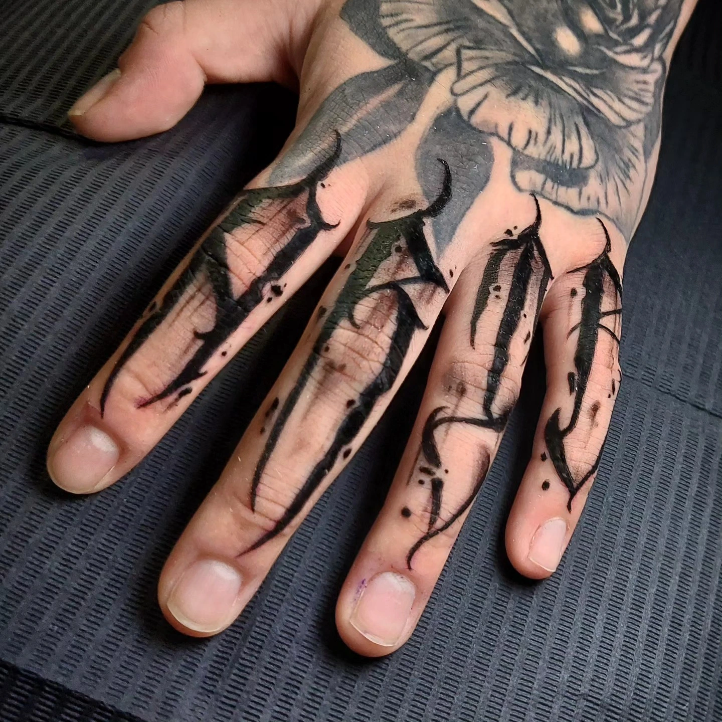 Tribal flame finger blackwork beneath rose