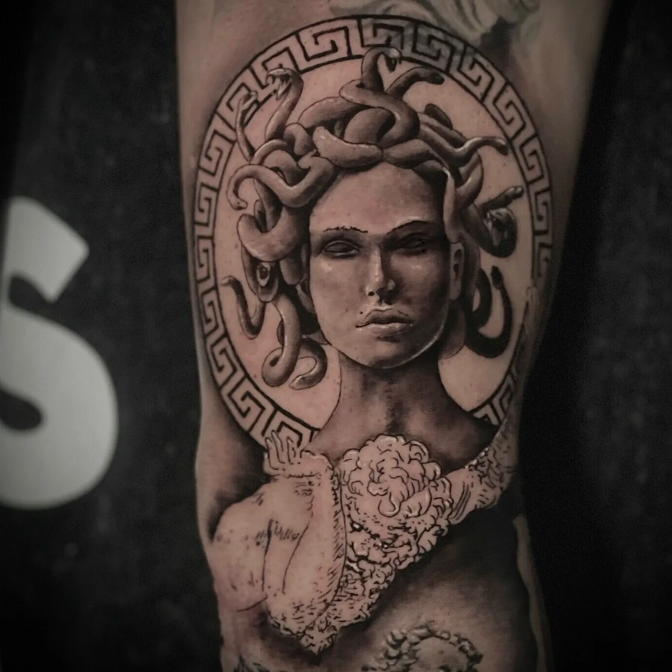 Medusa face inside Greek-key Versace-style frame circle